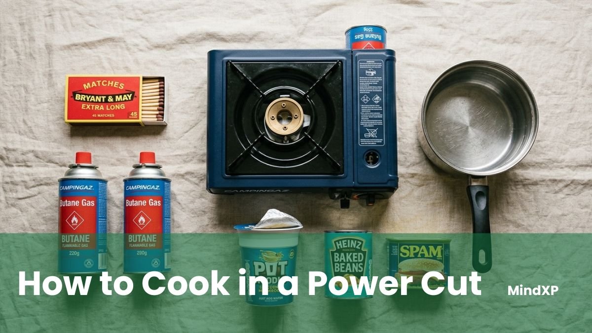 A power cut cooking kit laid out on a table: a camping stove, gas canisters, pots, a mess tin, and a cast-iron kettle.